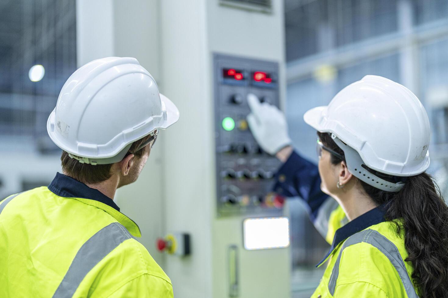 Male and female engineers in neat work clothes prepare and control the production system of large modern machines in a factory producing industrial technology products. photo