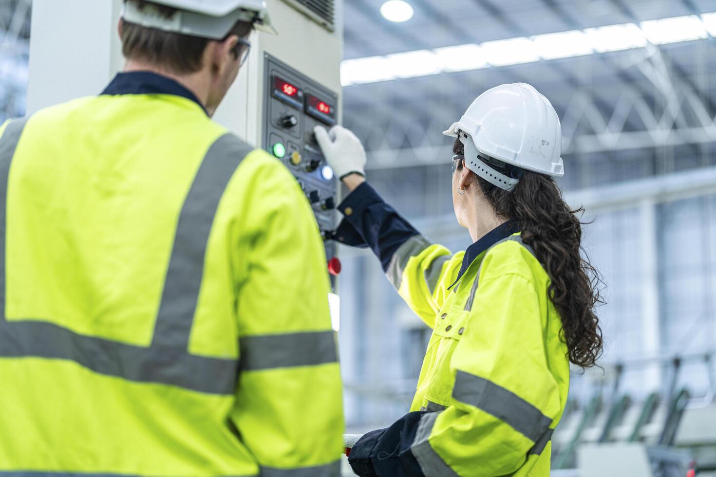 Male and female engineers in neat work clothes prepare and control the production system of large modern machines in a factory producing industrial technology products. photo