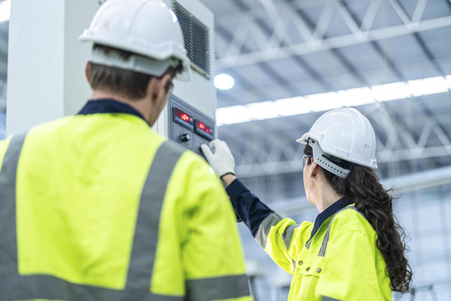 Male and female engineers in neat work clothes prepare and control the production system of large modern machines in a factory producing industrial technology products. photo