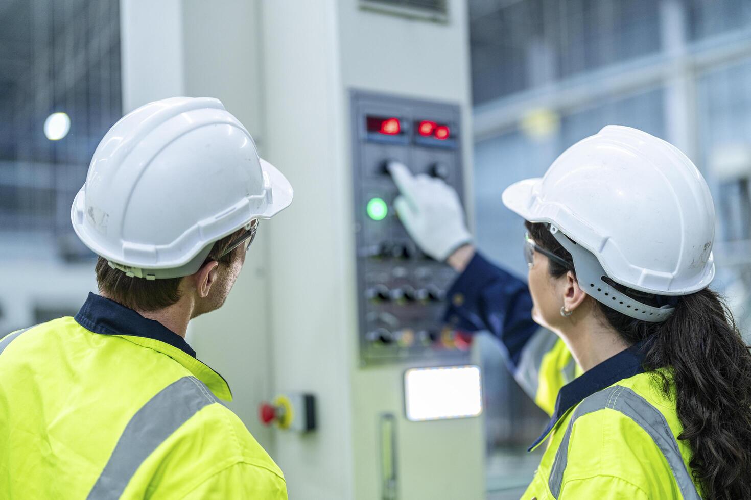 Male and female engineers in neat work clothes prepare and control the production system of large modern machines in a factory producing industrial technology products. photo