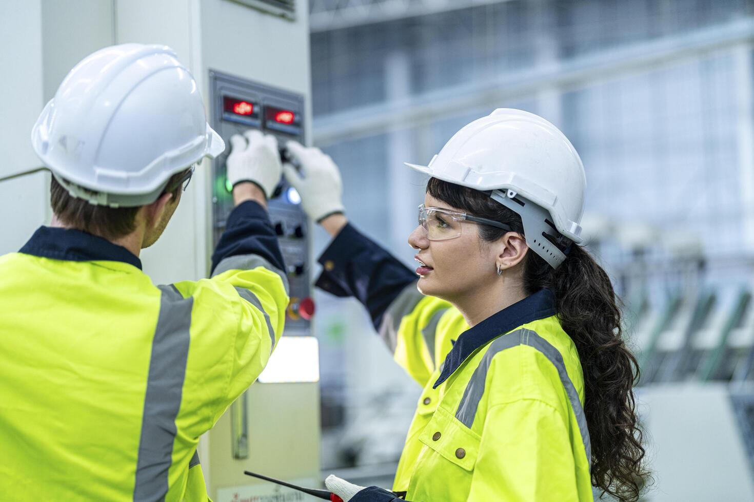 Male and female engineers in neat work clothes prepare and control the production system of large modern machines in a factory producing industrial technology products. photo