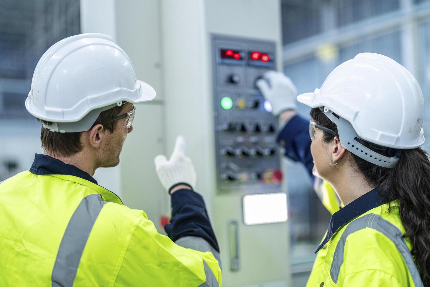 Male and female engineers in neat work clothes prepare and control the production system of large modern machines in a factory producing industrial technology products. photo