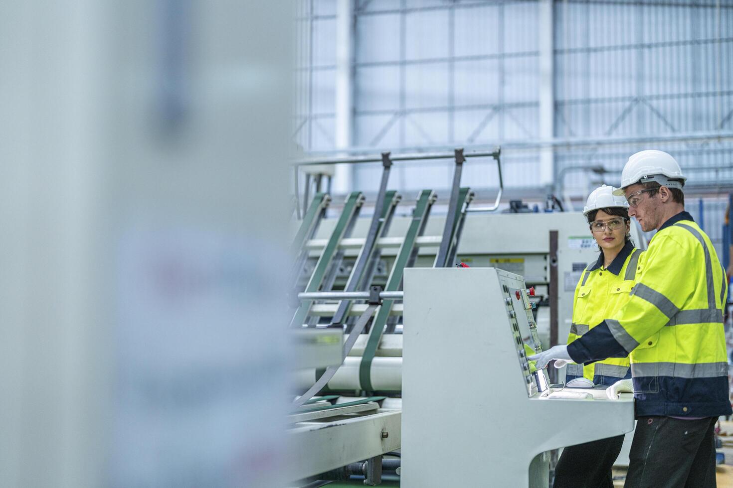 Male and female engineers in neat work clothes prepare and control the production system of large modern machines in a factory producing industrial technology products. photo