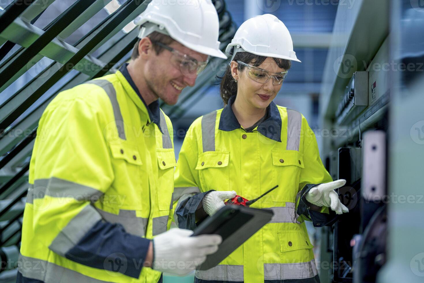 Male and female engineers in neat work clothes prepare and control the production system of large modern machines in a factory producing industrial technology products. photo