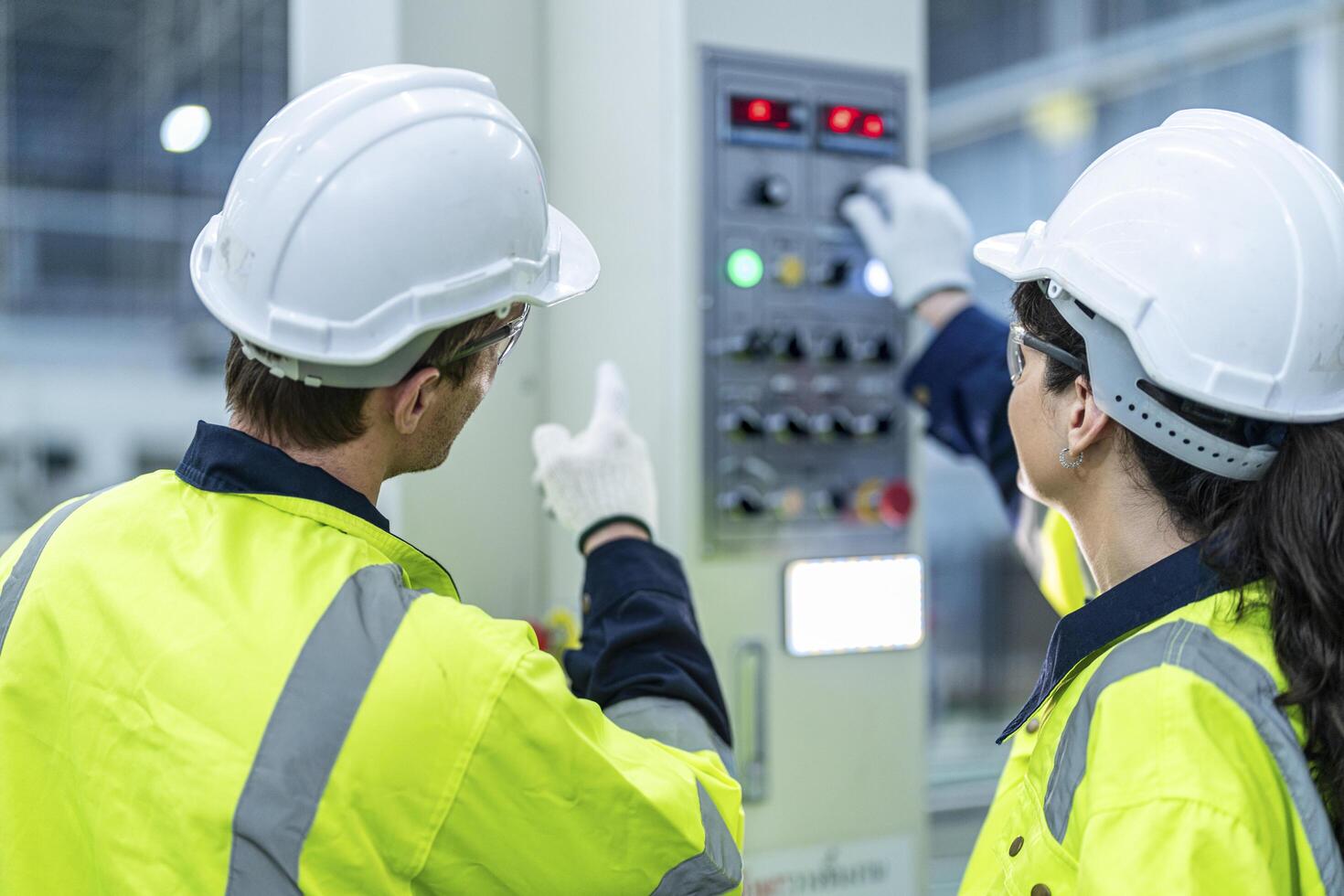 Male and female engineers in neat work clothes prepare and control the production system of large modern machines in a factory producing industrial technology products. photo