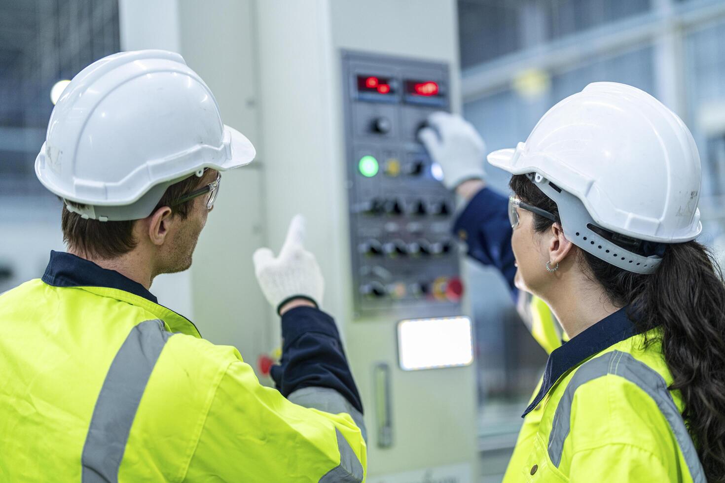 Male and female engineers in neat work clothes prepare and control the production system of large modern machines in a factory producing industrial technology products. photo