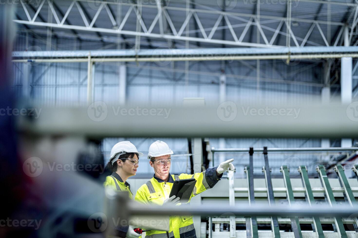 Male and female engineers in neat work clothes prepare and control the production system of large modern machines in a factory producing industrial technology products. photo