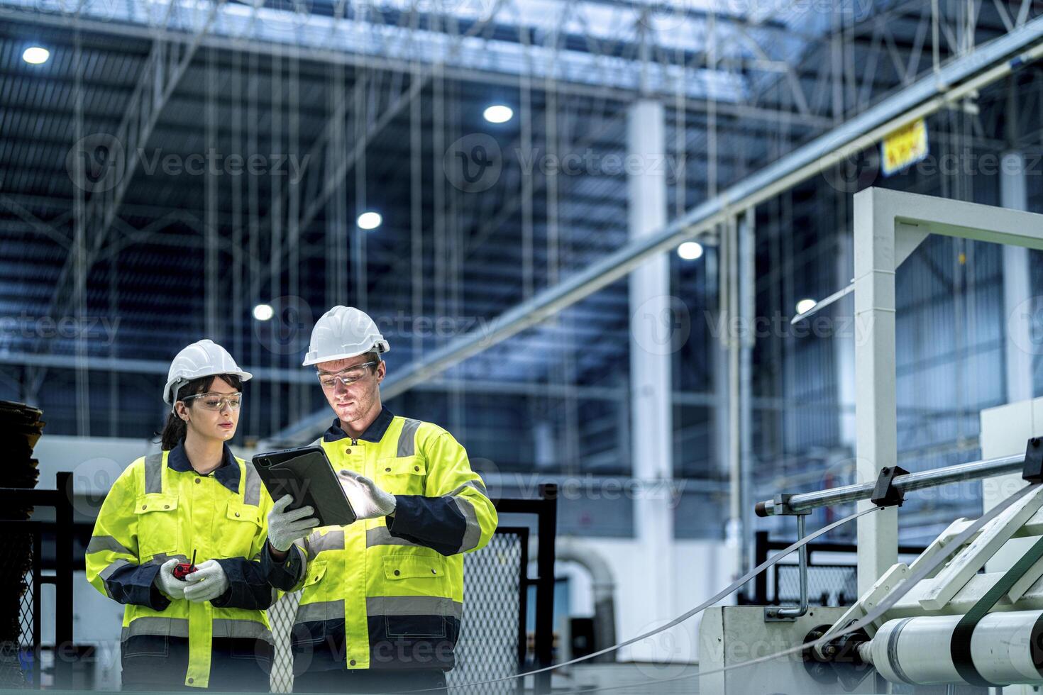 Male and female engineers in neat work clothes prepare and control the production system of large modern machines in a factory producing industrial technology products. photo