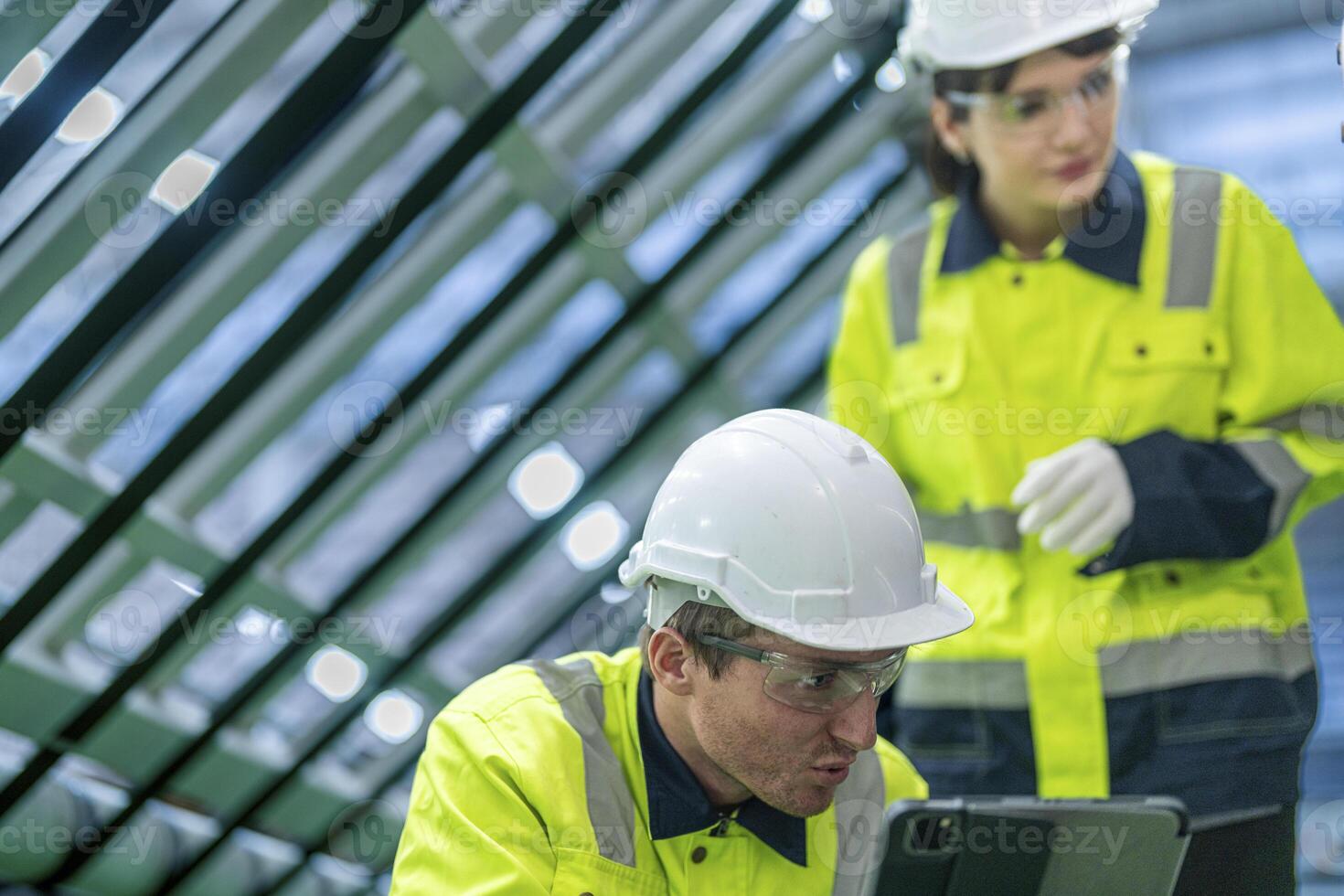 Male and female engineers in neat work clothes prepare and control the production system of large modern machines in a factory producing industrial technology products. photo