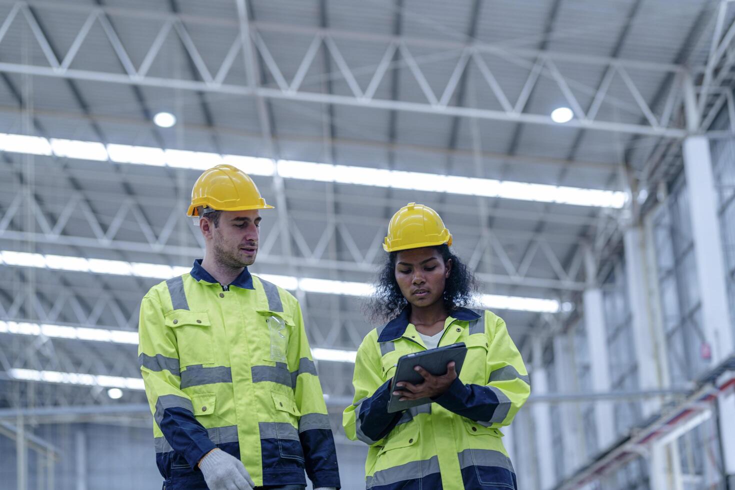 Male and female engineers in neat work clothes prepare and control the production system of large modern machines in a factory producing industrial technology products. photo
