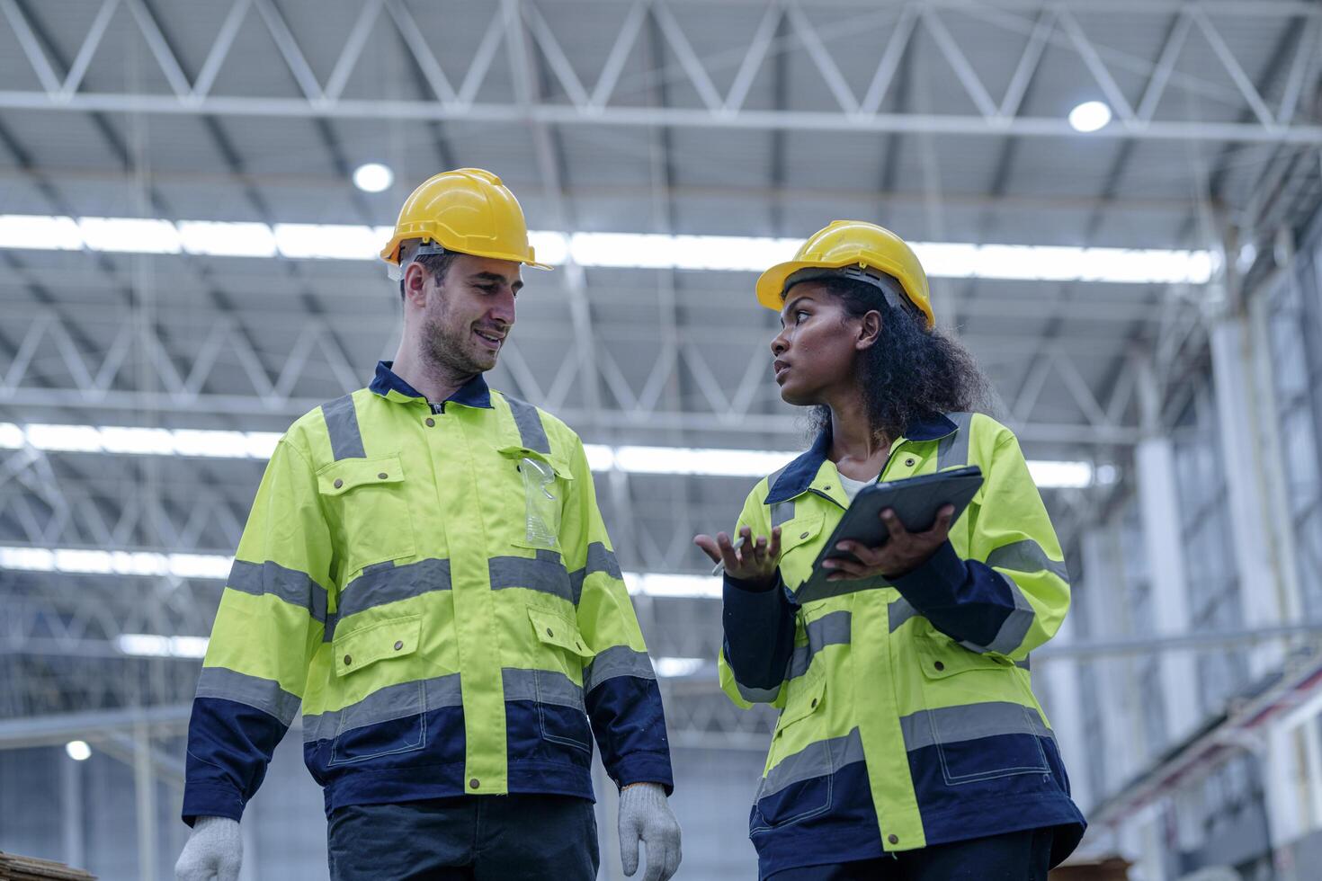 Male and female engineers in neat work clothes prepare and control the production system of large modern machines in a factory producing industrial technology products. photo