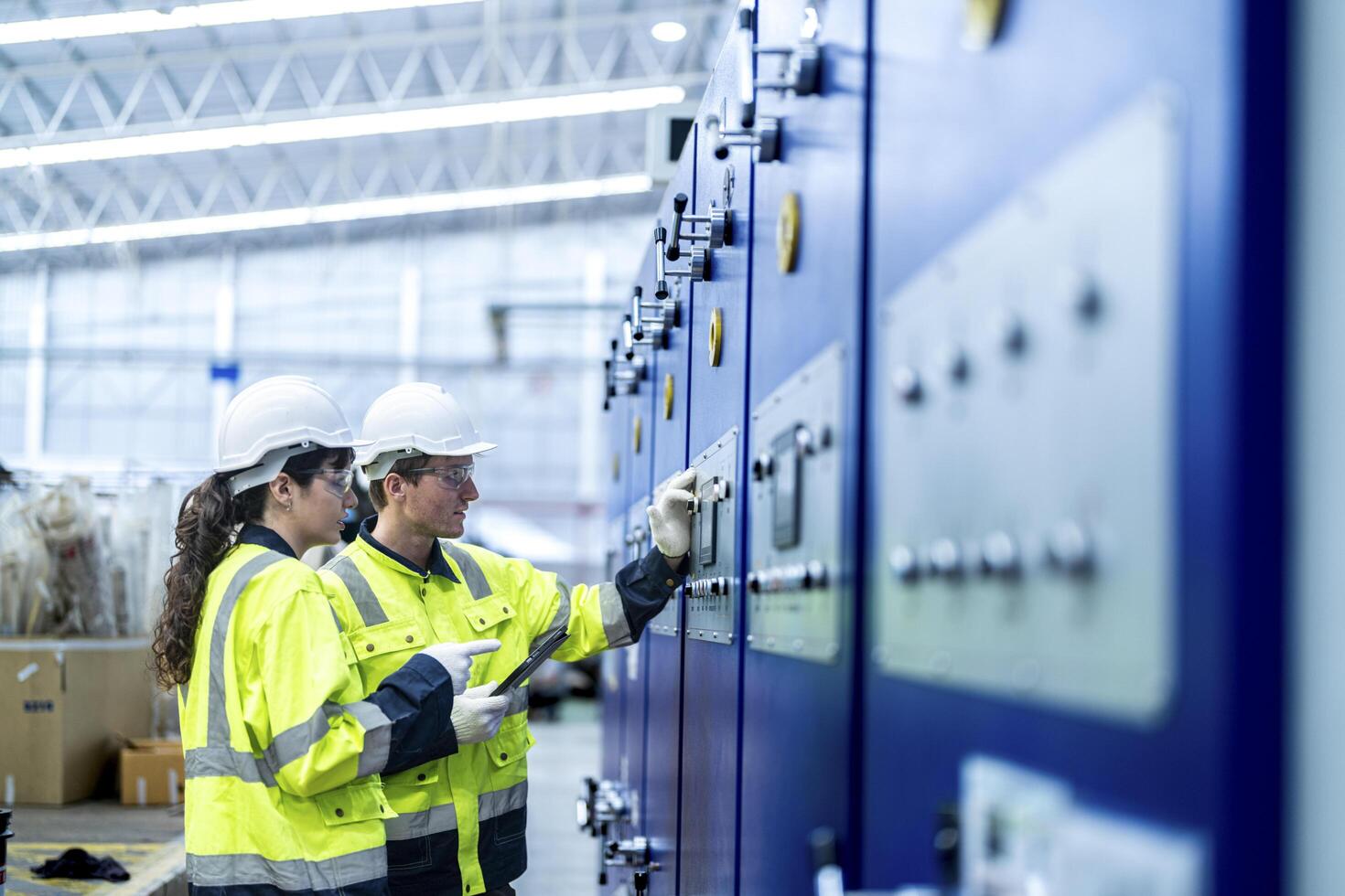 Male and female engineers in neat work clothes prepare and control the production system of large modern machines in a factory producing industrial technology products. photo