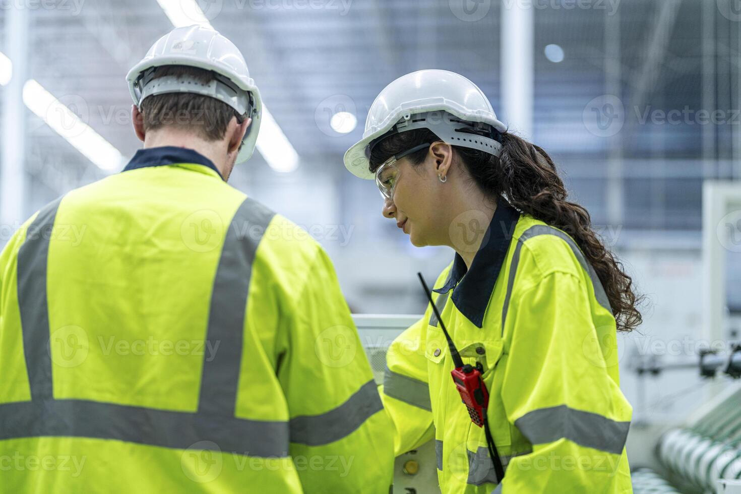 Male and female engineers in neat work clothes prepare and control the production system of large modern machines in a factory producing industrial technology products. photo