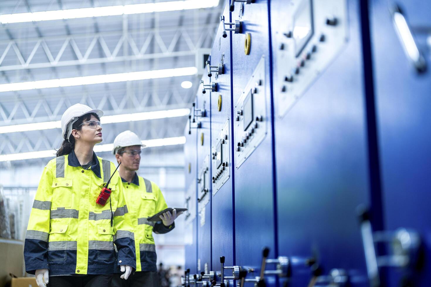 Male and female engineers in neat work clothes prepare and control the production system of large modern machines in a factory producing industrial technology products. photo