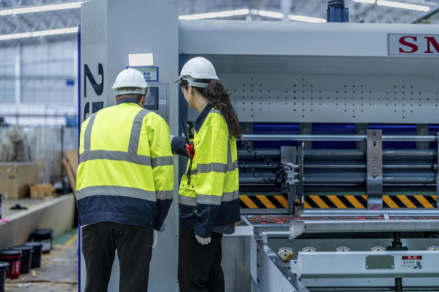 Male and female engineers in neat work clothes prepare and control the production system of large modern machines in a factory producing industrial technology products. photo