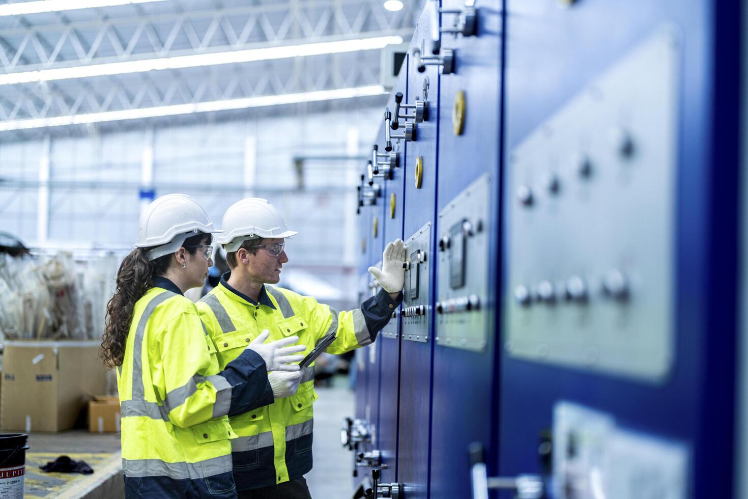 Male and female engineers in neat work clothes prepare and control the production system of large modern machines in a factory producing industrial technology products. photo