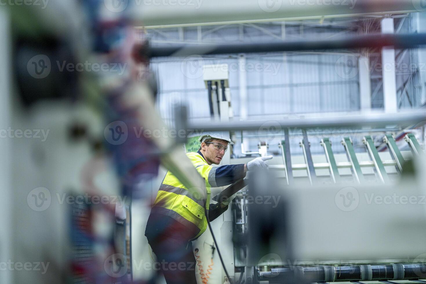 Male and female engineers in neat work clothes prepare and control the production system of large modern machines in a factory producing industrial technology products. photo