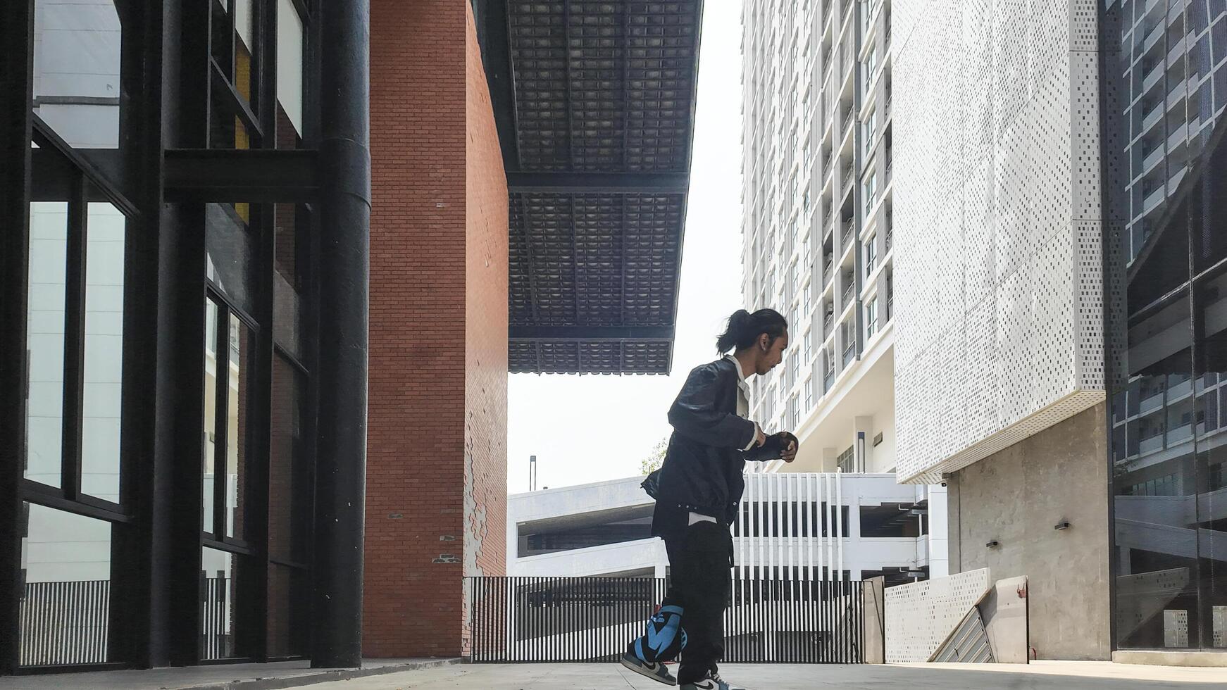 ASian man is dancing in hip hop style at outdoor space. Professional solo dancer is performing in public area. photo