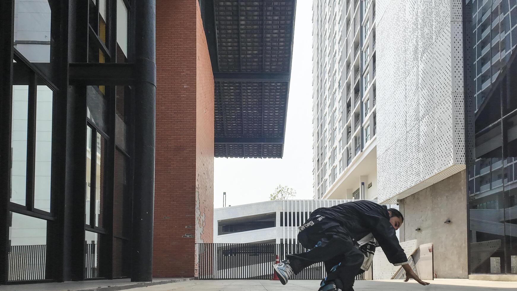 ASian man is dancing in hip hop style at outdoor space. Professional solo dancer is performing in public area. photo