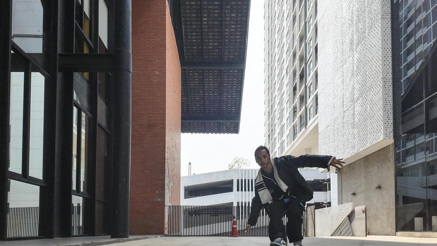 ASian man is dancing in hip hop style at outdoor space. Professional solo dancer is performing in public area. photo