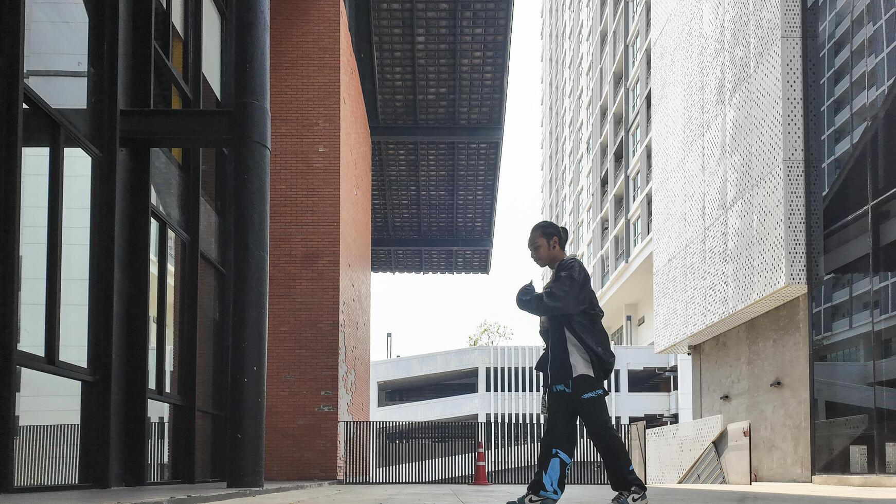ASian man is dancing in hip hop style at outdoor space. Professional solo dancer is performing in public area. photo