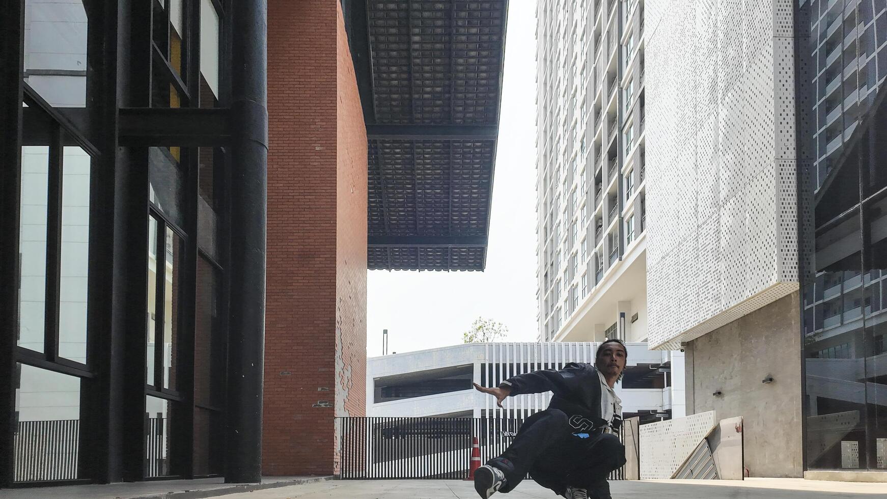 ASian man is dancing in hip hop style at outdoor space. Professional solo dancer is performing in public area. photo