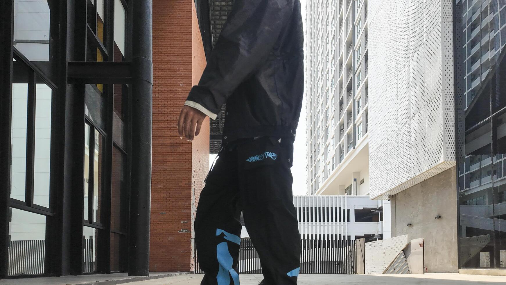 ASian man is dancing in hip hop style at outdoor space. Professional solo dancer is performing in public area. photo