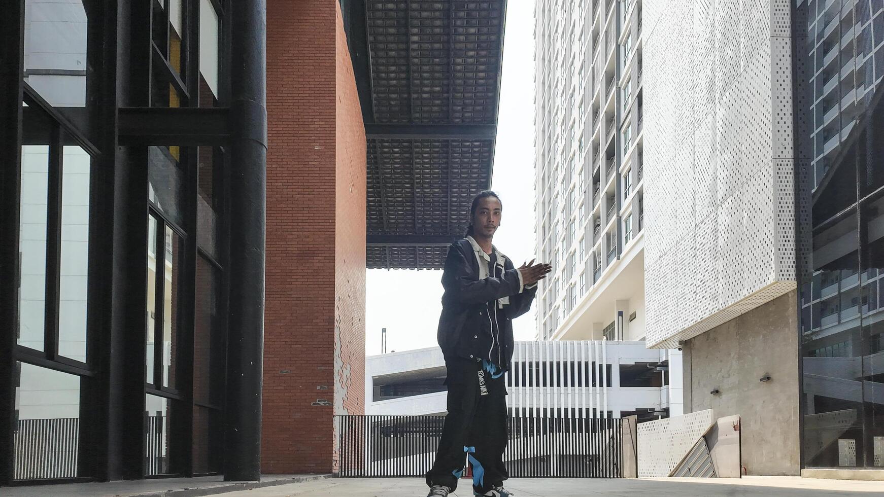 ASian man is dancing in hip hop style at outdoor space. Professional solo dancer is performing in public area. photo
