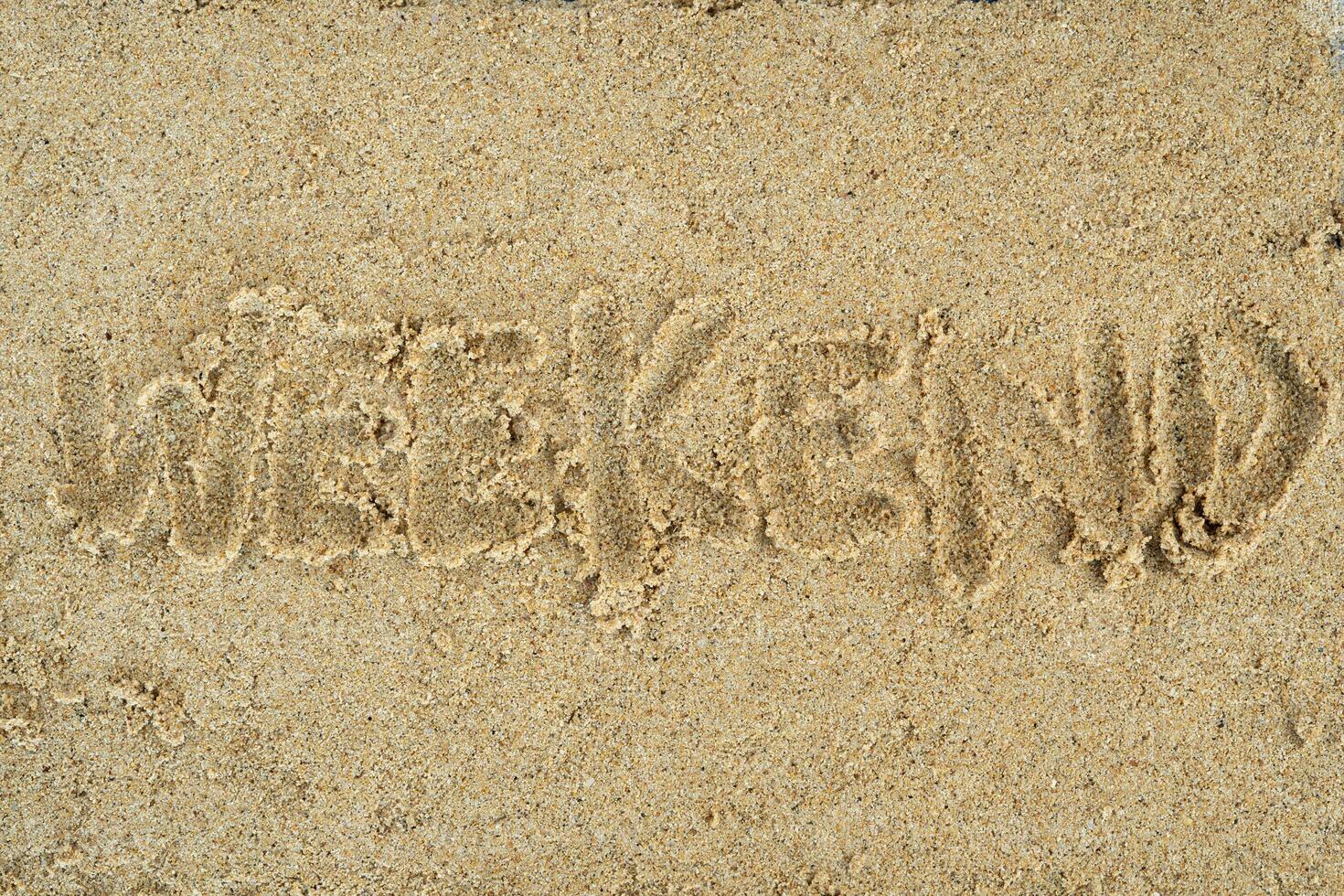 weekend hand writing on sand background photo