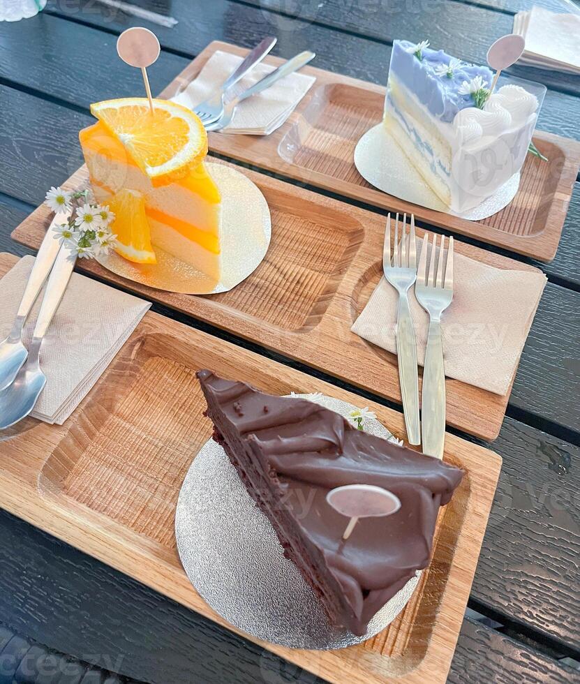 A slice of coconut, chocolate and orange cake served on a wooden tray with a fork photo