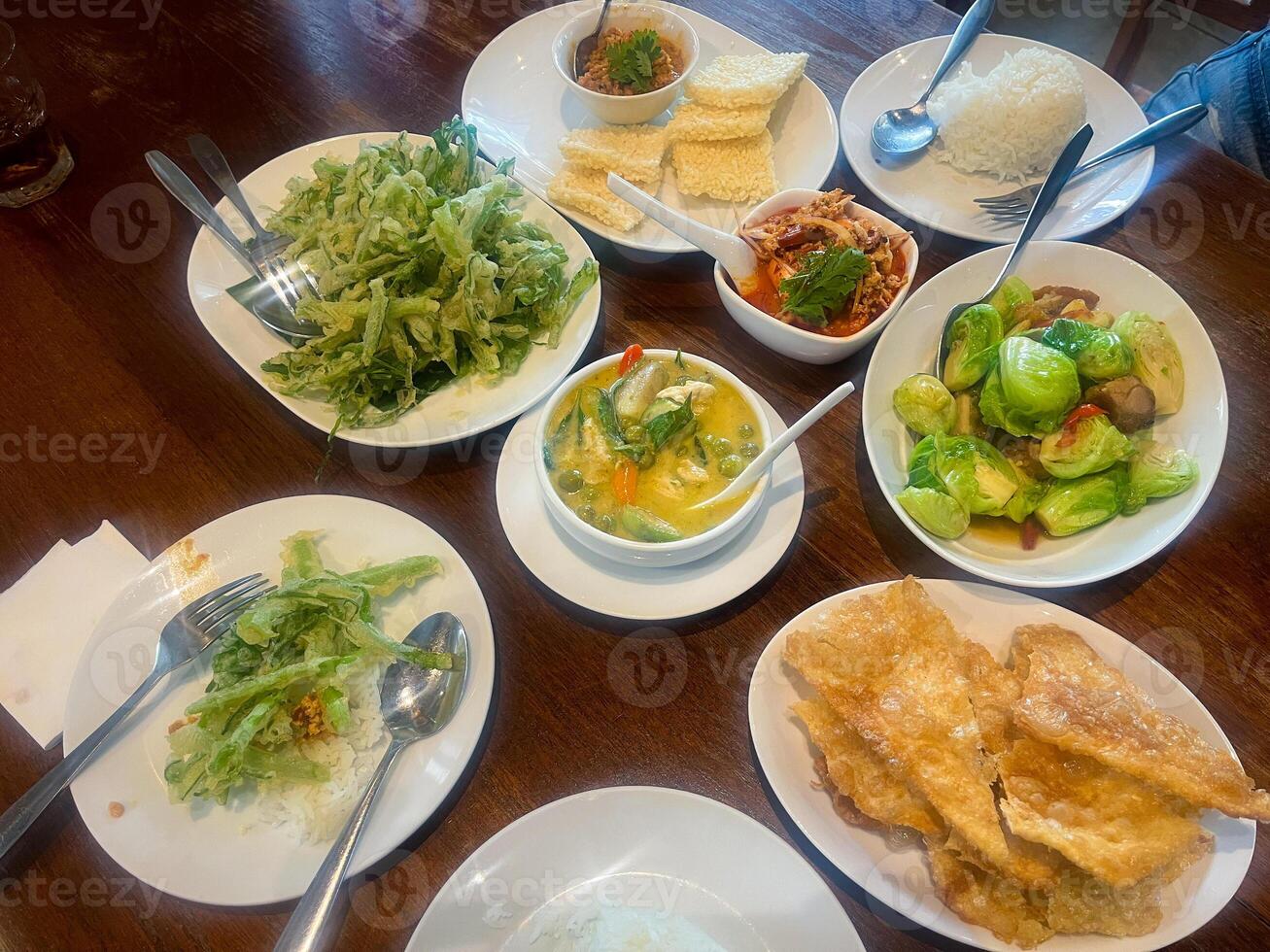 A large dinner with many dishes. such as green curry Crispy morning glory salad, roti, stir-fried cabbage and chili paste photo