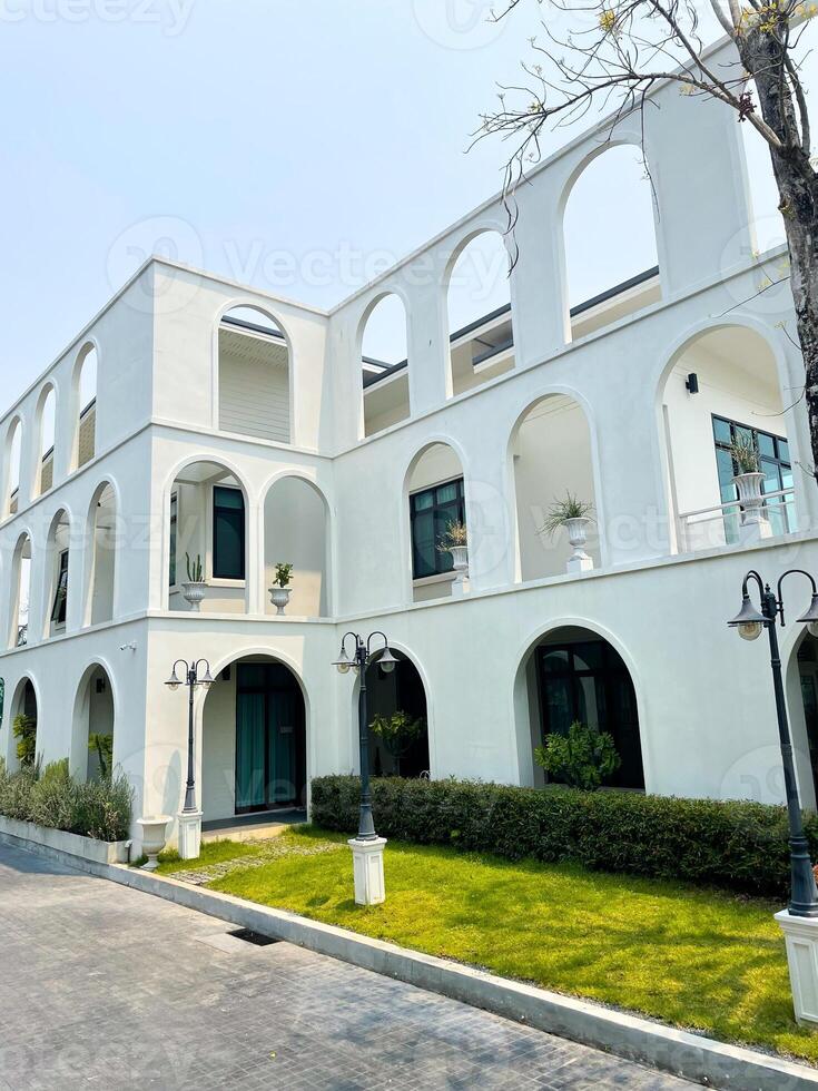 Modern white townhouses, large with 3 floors, front with a lamp post and a small garden photo