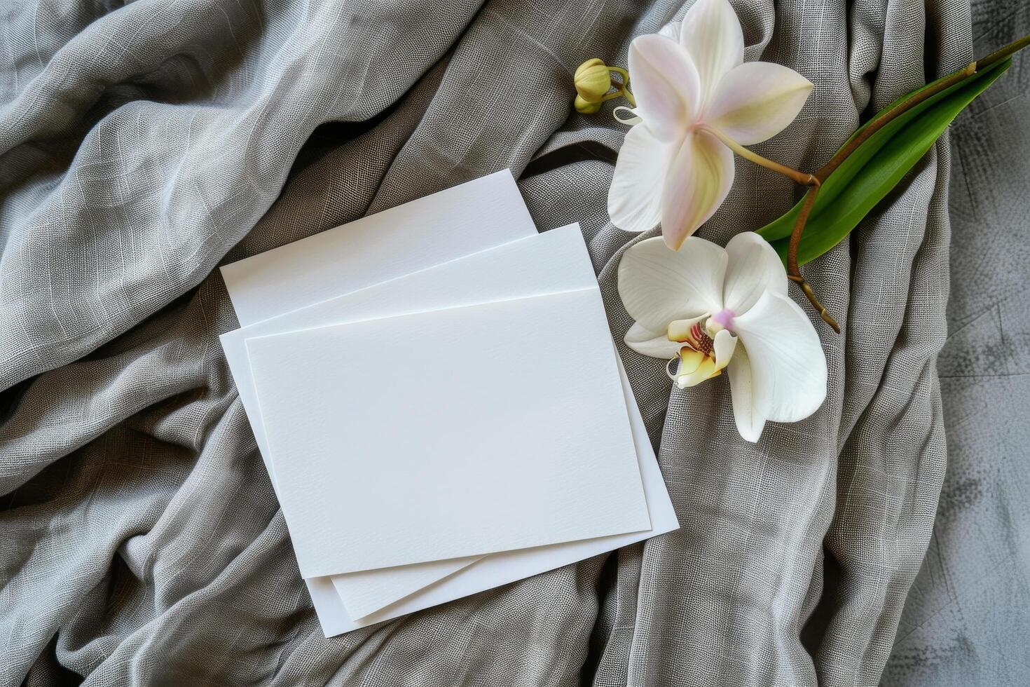Blank White Cards Resting on a Soft Beige Fabric With White Orchids photo