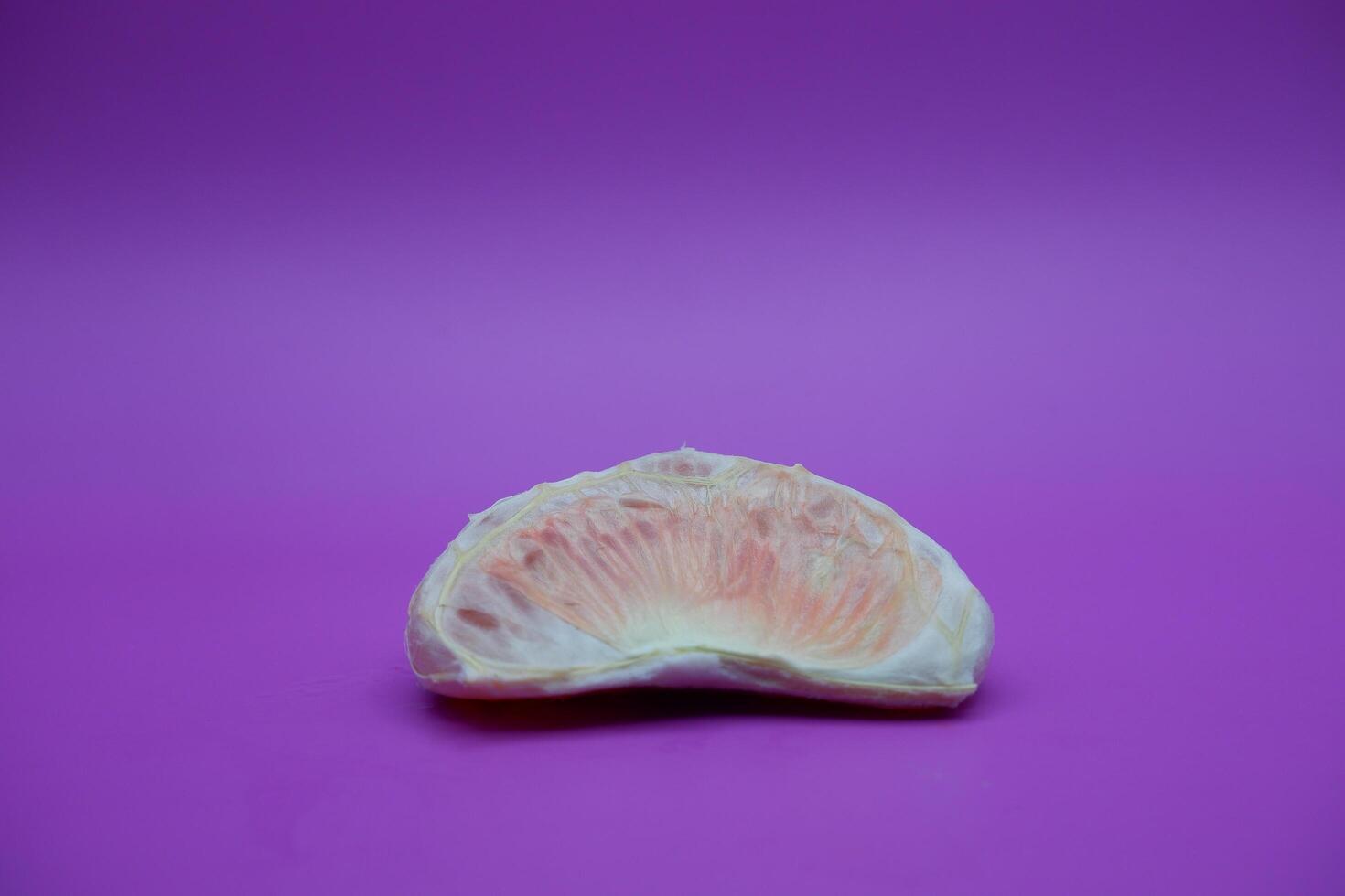 a slice of grapefruit isolated on a purple background. peeled grapefruit photo