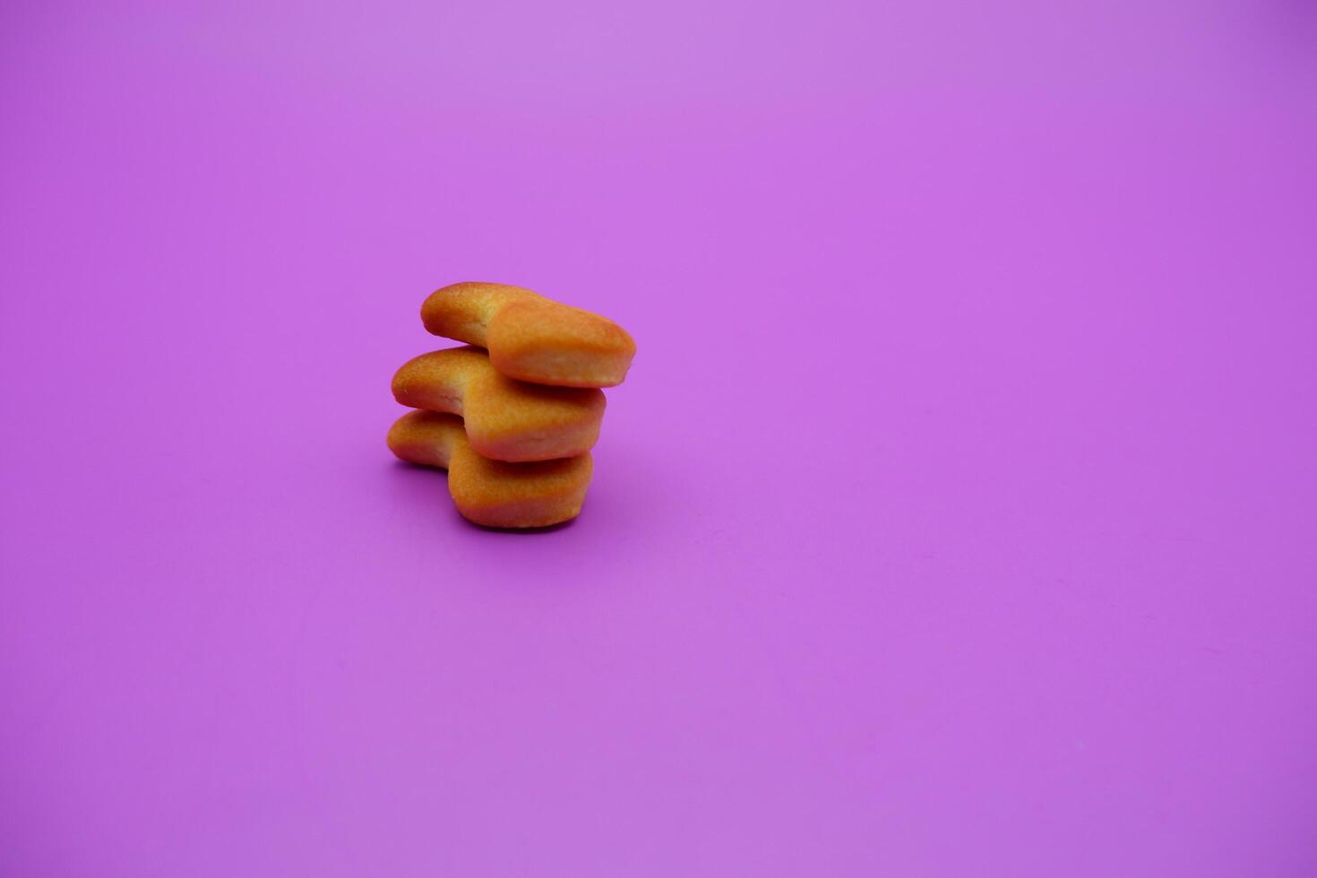 three biscuits shaped like fish isolated on a purple background photo