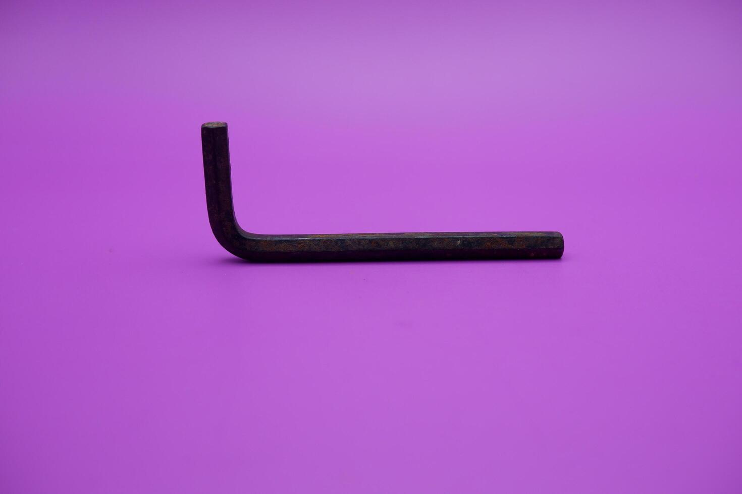 Allen key isolated purple background. a black L key. photo