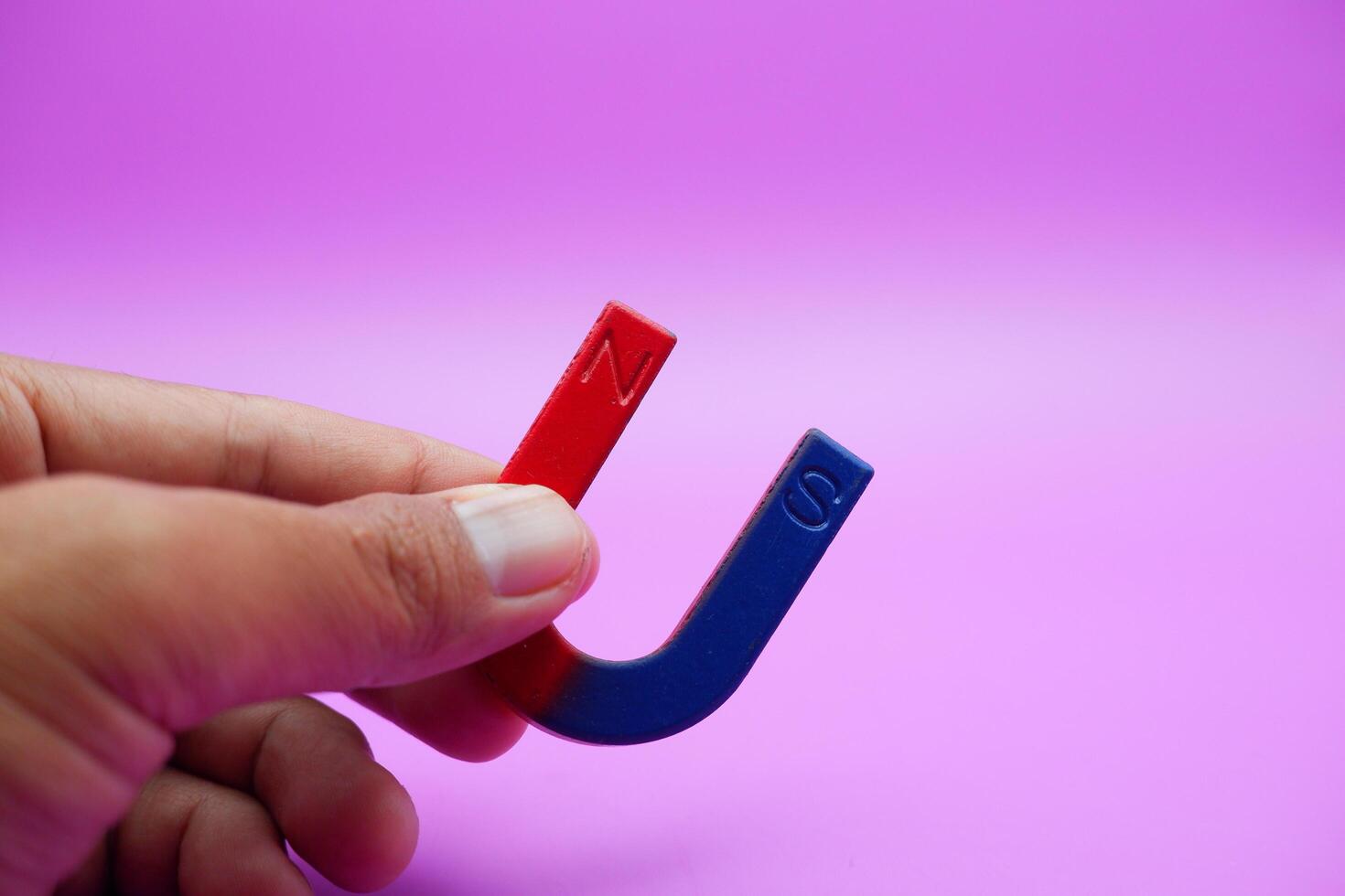 hand holding a horseshoe magnet isolated on a purple background photo