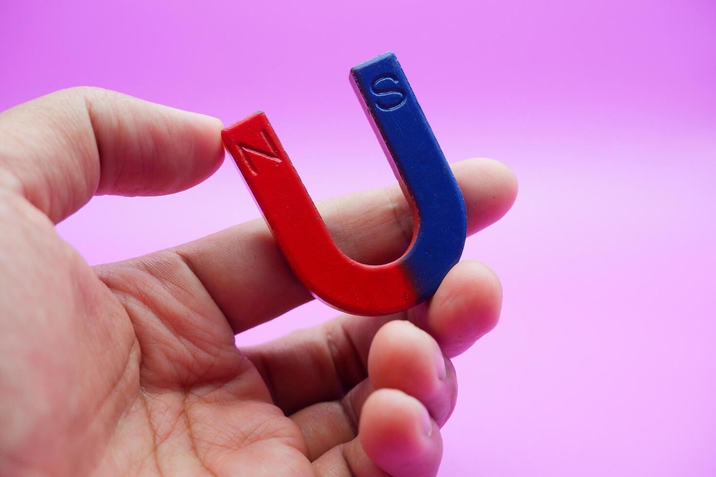 hand holding a horseshoe magnet isolated on a purple background photo