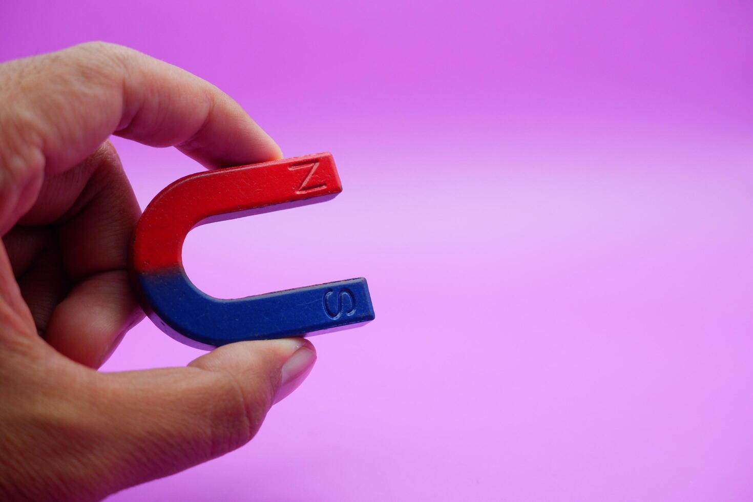 hand holding a horseshoe magnet isolated on a purple background photo