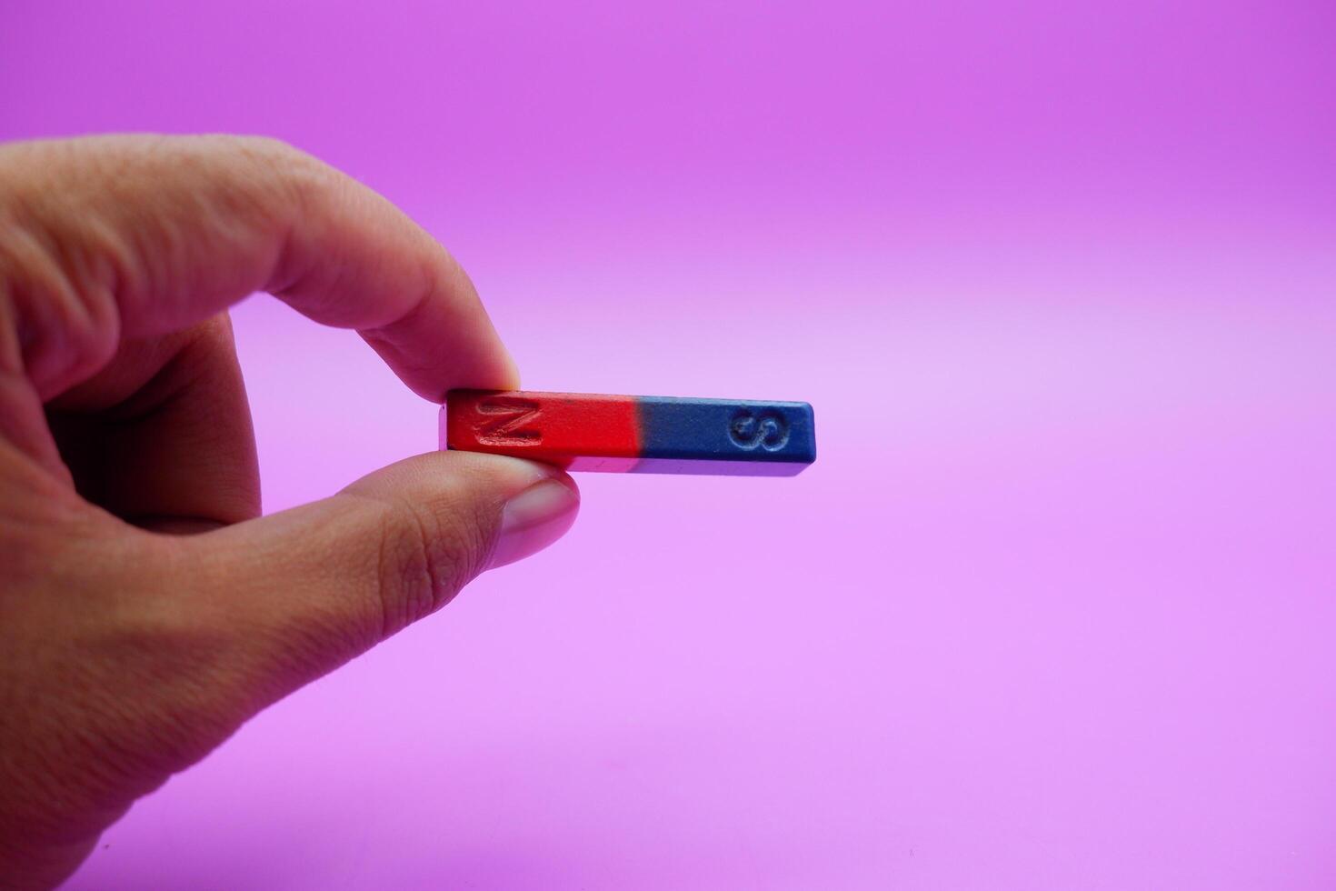 hand holding a bar magnet isolated on a purple background photo
