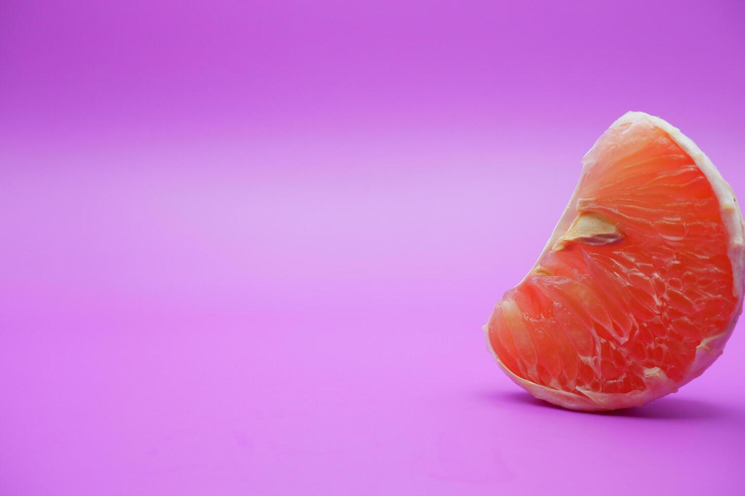 a slice of grapefruit isolated on a purple background. grapefruit that has been peeled until the grain of the orange is visible photo
