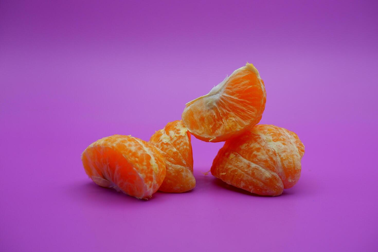 oranges that have been peeled and divided into several parts. orange isolated on purple background photo