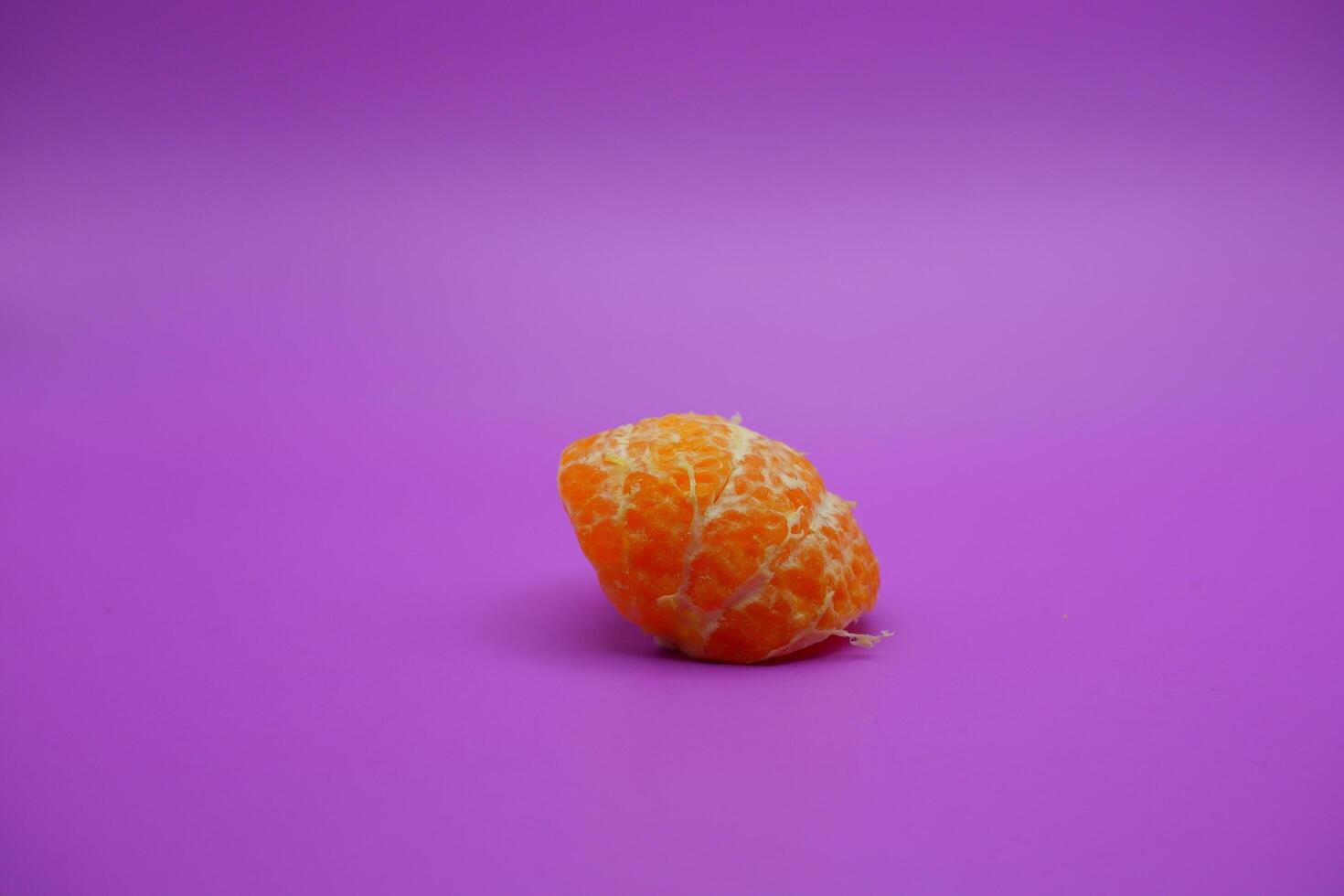 oranges that have been peeled and divided into small parts. orange isolated on purple background photo