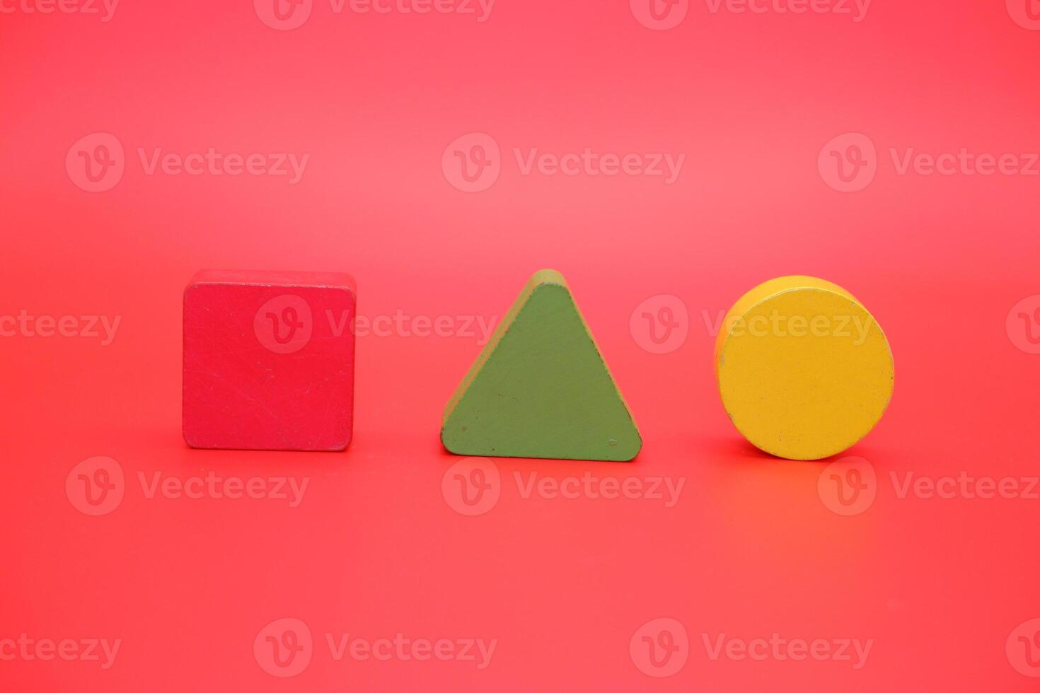 colorful wooden toys isolated red background. wooden toys shaped like triangles, squares and circles. photo