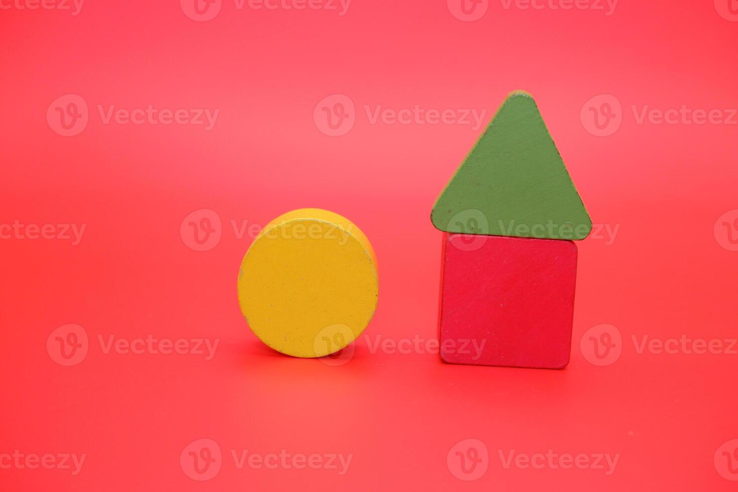 colorful wooden toys isolated red background. wooden toys shaped like triangles, squares and circles. photo