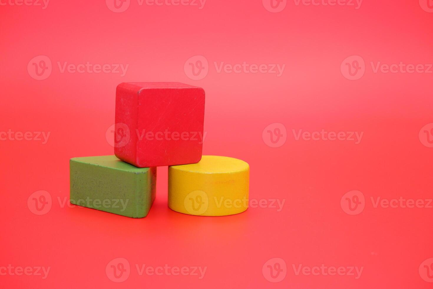 colorful wooden toys isolated red background. wooden toys shaped like triangles, squares and circles. photo