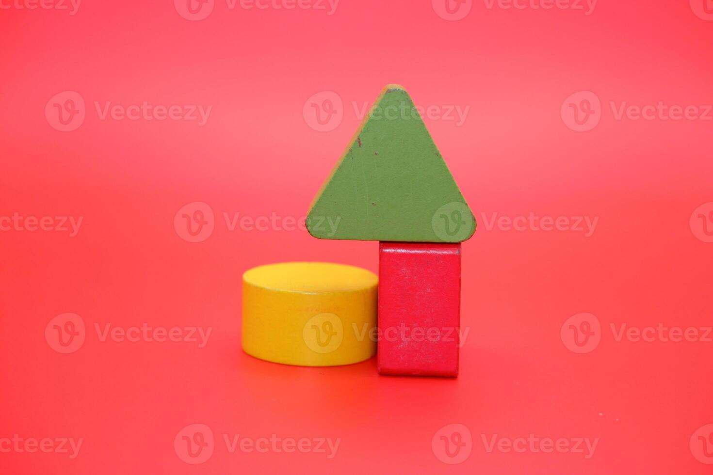 colorful wooden toys isolated red background. wooden toys shaped like triangles, squares and circles. photo