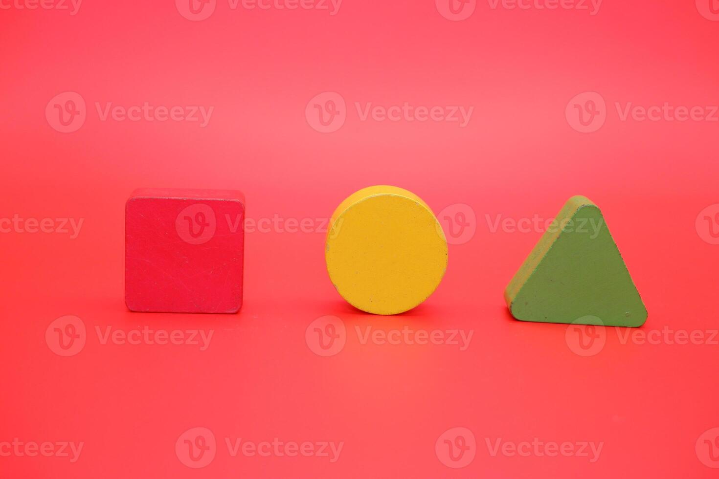 colorful wooden toys isolated red background. wooden toys shaped like triangles, squares and circles. photo