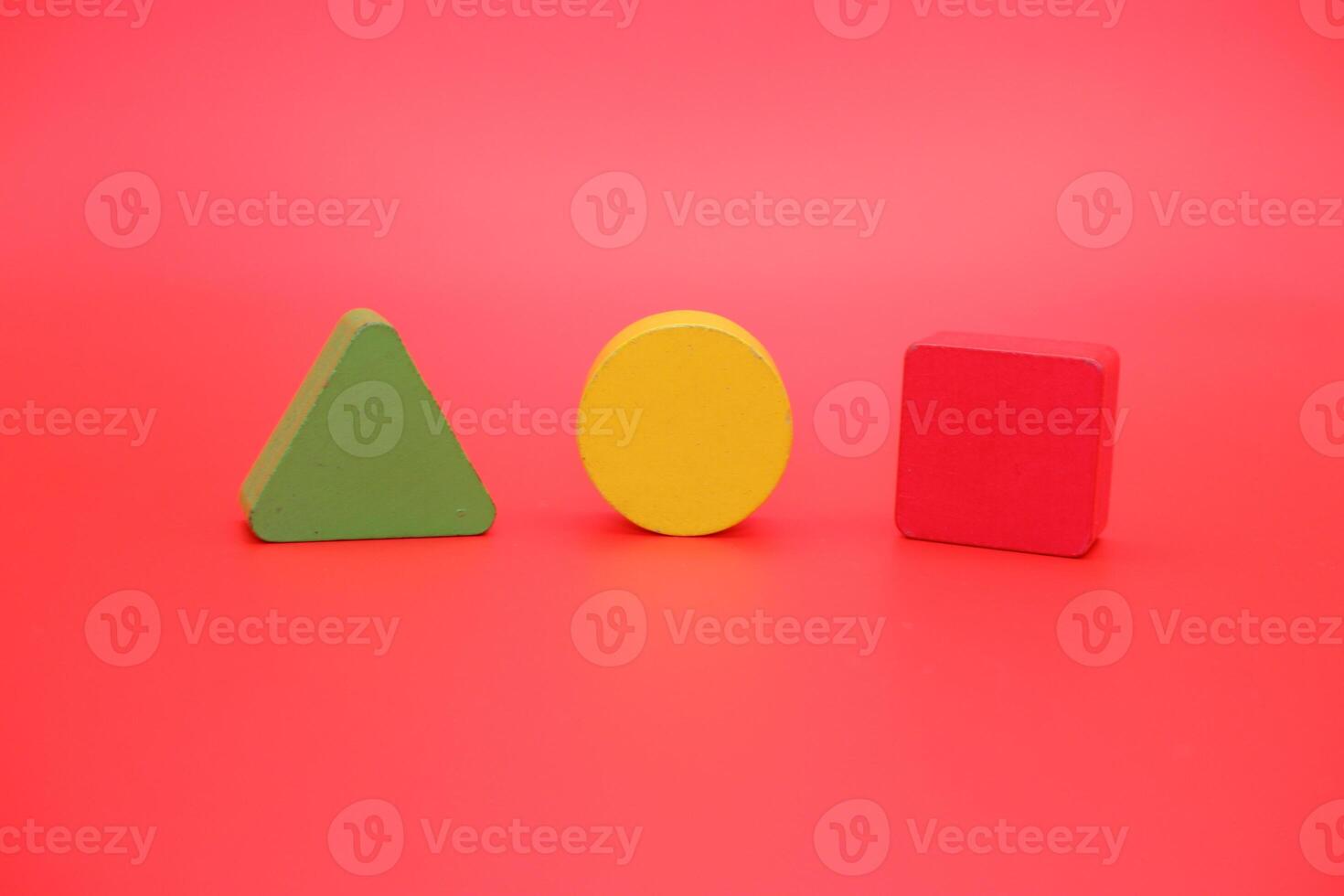 colorful wooden toys isolated red background. wooden toys shaped like triangles, squares and circles. photo
