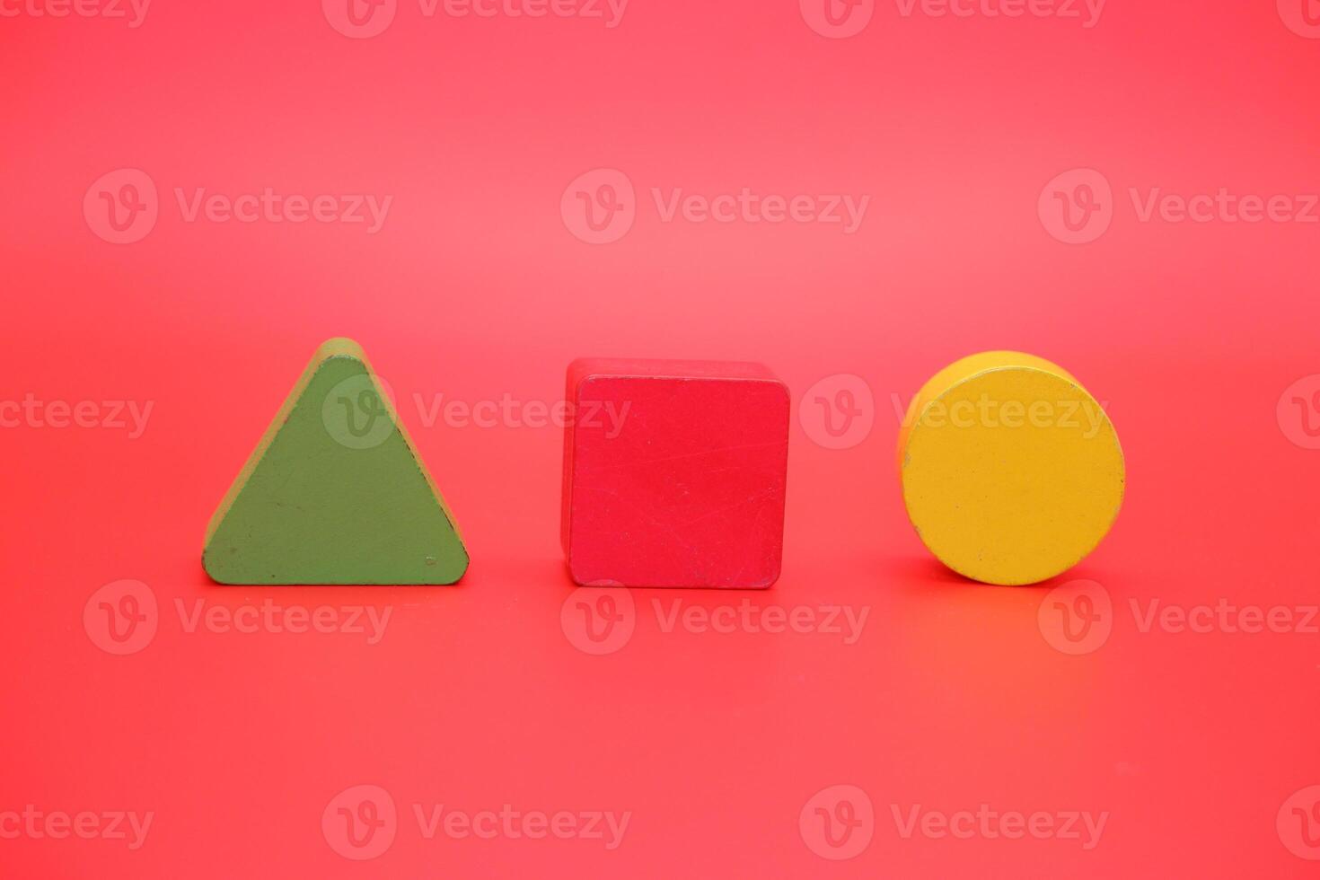colorful wooden toys isolated red background. wooden toys shaped like triangles, squares and circles. photo